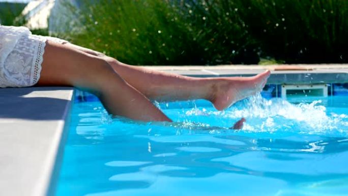 在阳光明媚的日子里，低矮的女人将脚浸入游泳池4k