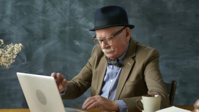 现代老人在笔记本电脑上工作