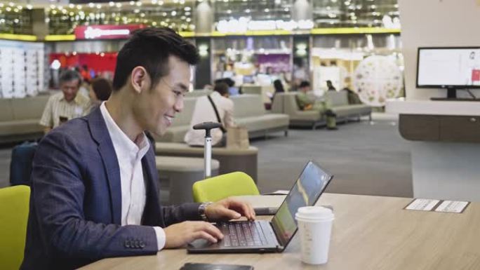休闲亚洲商人在机场使用笔记本电脑