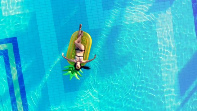 一个人坐在游泳池里，漂浮在橡胶床垫上。游泳池里无忧无虑的女士。