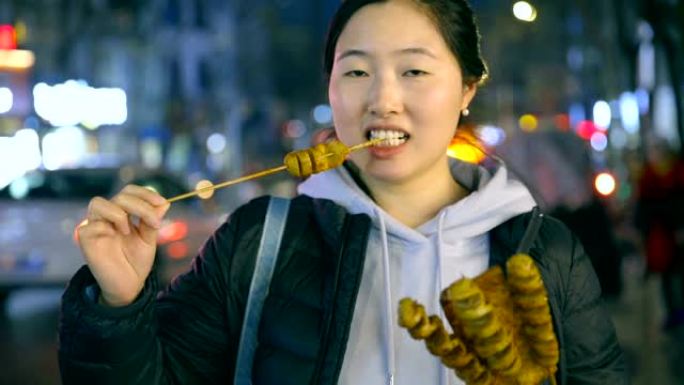 亚洲年轻女子晚上享受街头美食