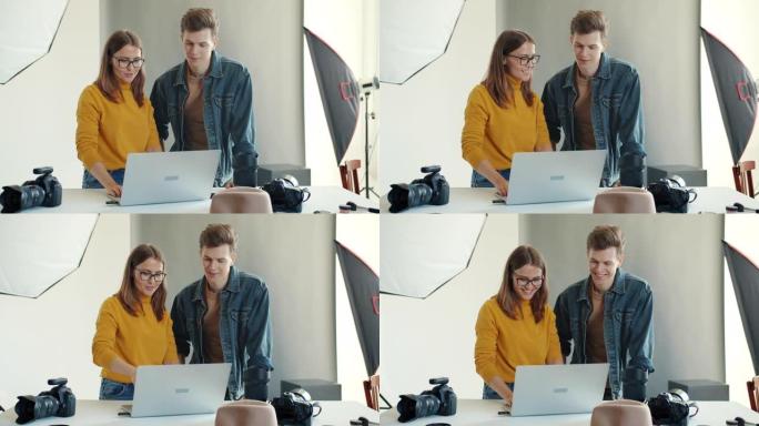 快乐的男人和女人在摄影棚里使用笔记本电脑，在拍照后观看照片