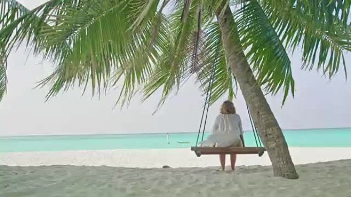 宁静的女士在马尔代夫热带海洋海滩田园诗般的棕榈树上摇摆