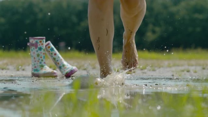 SLO MO赤脚女人在泥泞的水坑里飞溅。幸福的女人。