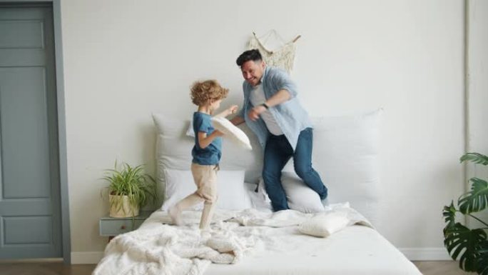 父亲和儿子在床上玩耍战斗枕头掉下来然后母亲回家