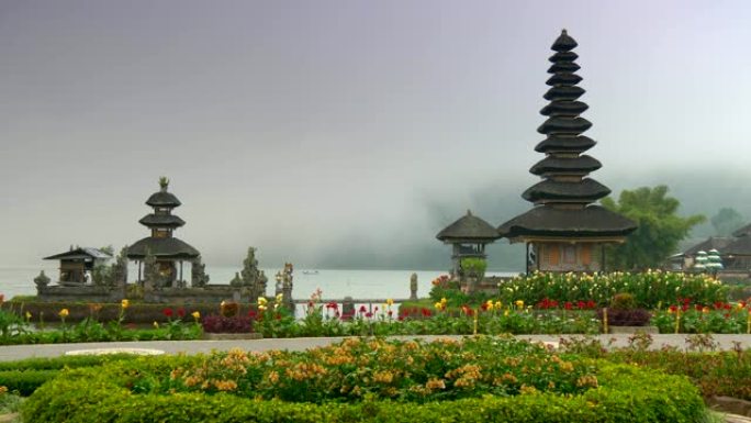 印度尼西亚巴厘岛。Pura Ulun Danu Bratan寺被美丽的花朵包围，背景为薄雾覆盖的水。