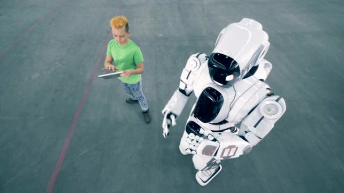 一个机器人移动，而一个男孩控制。未来主义人形机器人