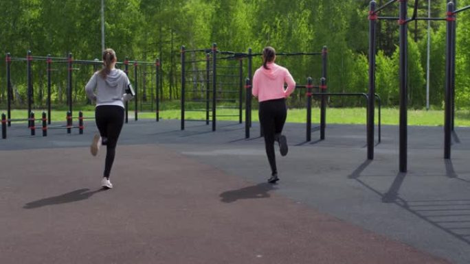 运动型双胞胎姐妹在户外健身房慢跑