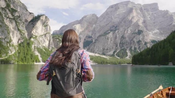 一个美丽的女人在木凳上徒步旅行。这个女人对周围的风景感到高兴和热情，并钦佩他。