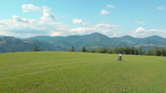 无人机: 运动游客在风景秀丽的阳光明媚的大自然中踩踏下坡自行车。