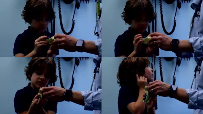 年轻的亚洲男医生在诊所4k向白人男孩患者展示耳朵模型的侧视图