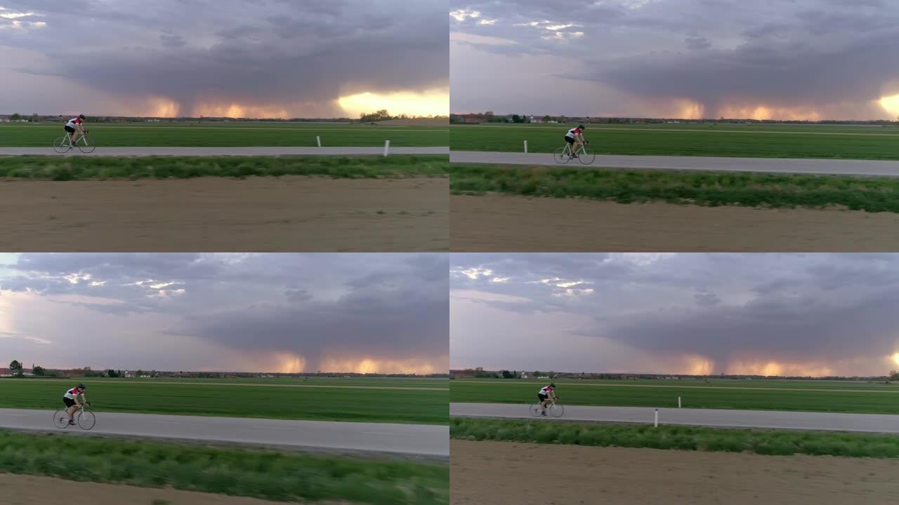WS男骑自行车者在乡村道路上骑自行车，背景为暴风云