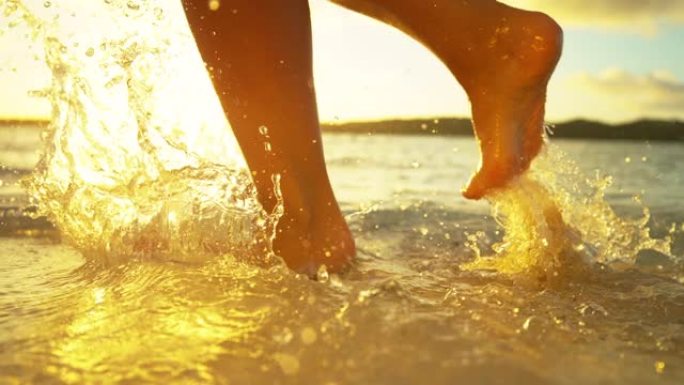 镜头耀斑: 金色的夕阳照耀着在浅海水中行走的赤脚女孩。