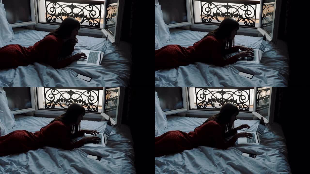 高角度快乐的高加索作家躺在法国阳台床上在笔记本电脑上打字，寻找创意灵感慢动作