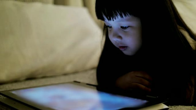 慢动作: 小女孩睡觉前晚上在平板电脑上观看娱乐媒体