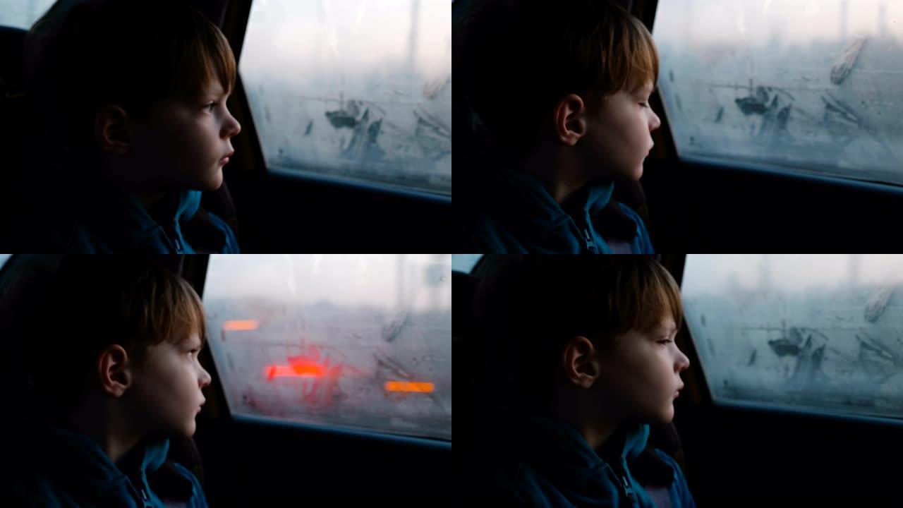 3-6岁可爱的悲伤的高加索男孩在黑暗的夜晚骑行中从雾蒙蒙的车窗向外看的电影镜头。