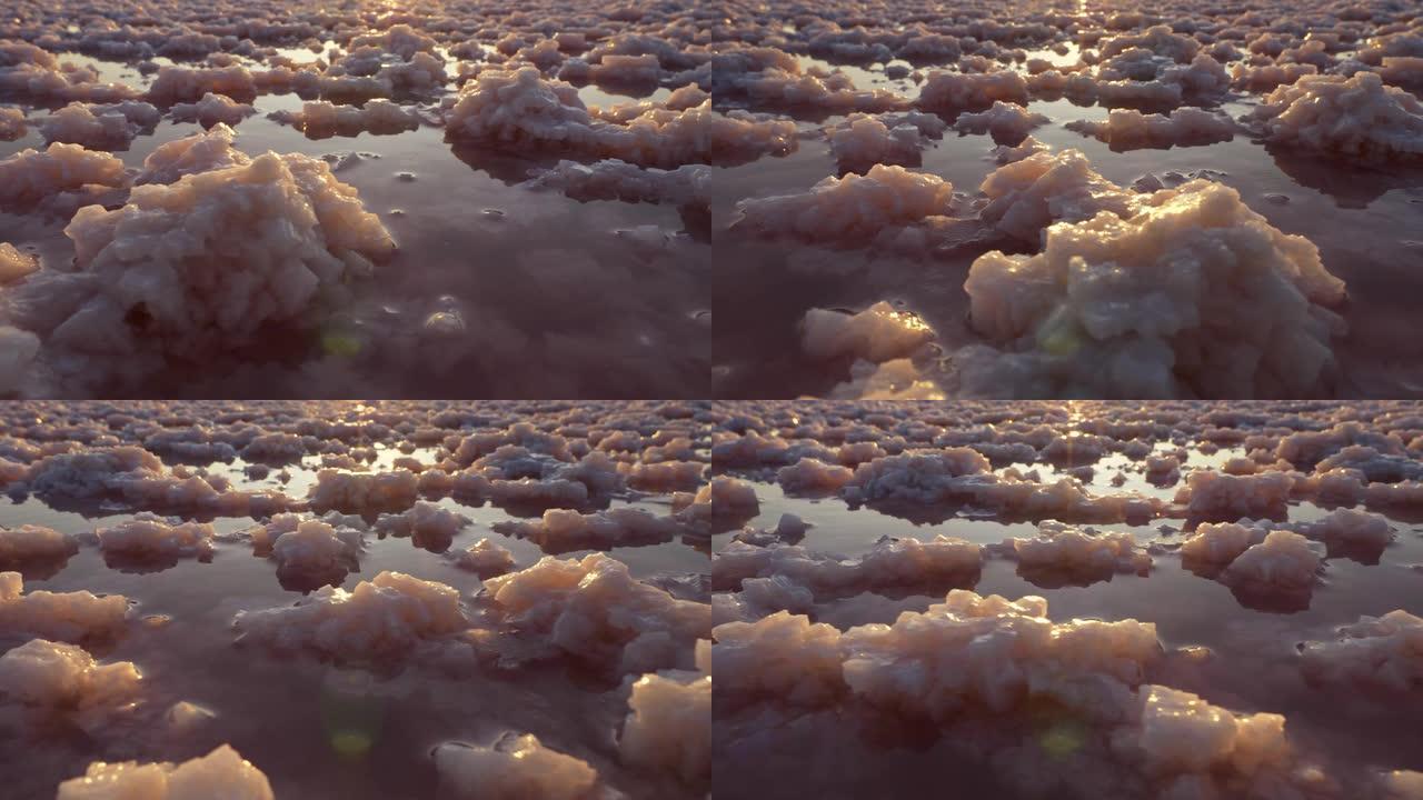 日落时粉红色盐湖中的盐晶块。UHD