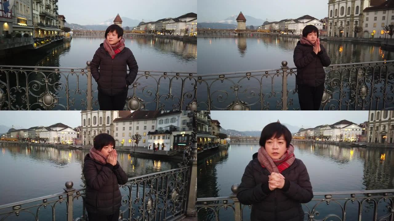 一名在老城区桥上的亚洲华裔女游客在黄昏时感到寒冷