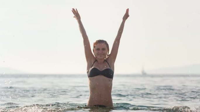 年轻女子站在海中向空中喷洒海水