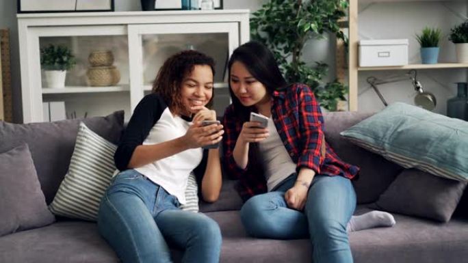 微笑的年轻女性正在使用智能手机聊天和大笑，看着屏幕享受社交媒体和现代技术。沟通与青年观念。
