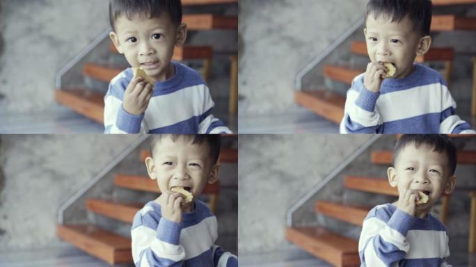 4k慢动作镜头亚洲小男孩吃一口饼干和饼干，微笑着充满幸福的现代阁楼房子生活，家庭和生活方式概念