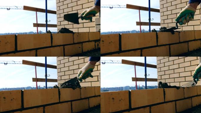 一个人在盖房子时砌砖。瓦工在建筑工地做砖砌。
