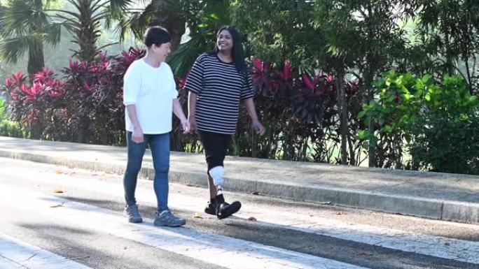 一名亚洲印度残障人士假肢运动女子在公园晨间与一名活跃的中国高级女子慢跑