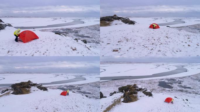 WS妇女在冰岛偏远景观的白雪覆盖的山上调整露营帐篷