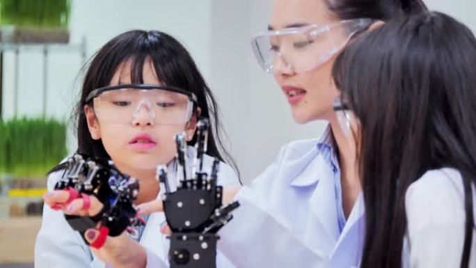 教师和小组儿童为学校机器人俱乐部项目工作一个功能齐全的可编程机器人手臂。创意设计师在车间测试机器人原
