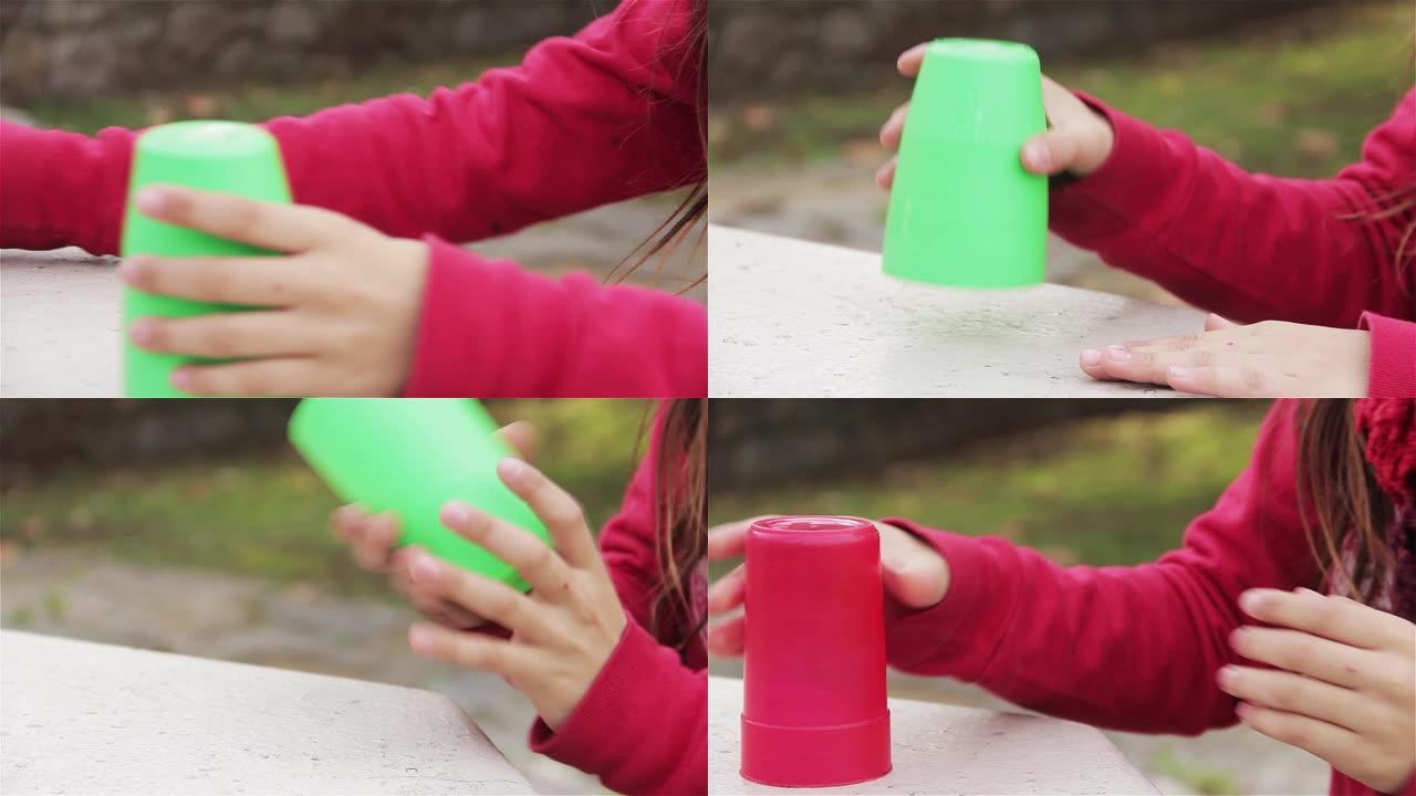 玩塑料杯的年轻女孩。