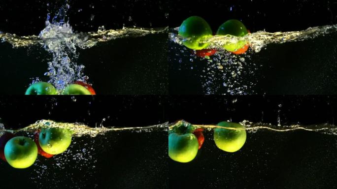 绿苹果和红苹果随气泡落入水中的慢动作视频。孤立的黑色背景上的水果。