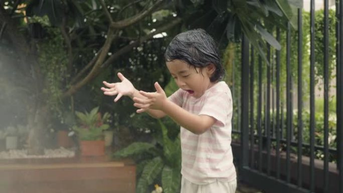 亚洲宝宝在家前院微笑着玩水。