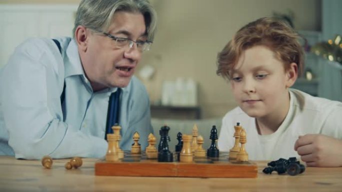 老人和他的孙子正在仔细观察棋子