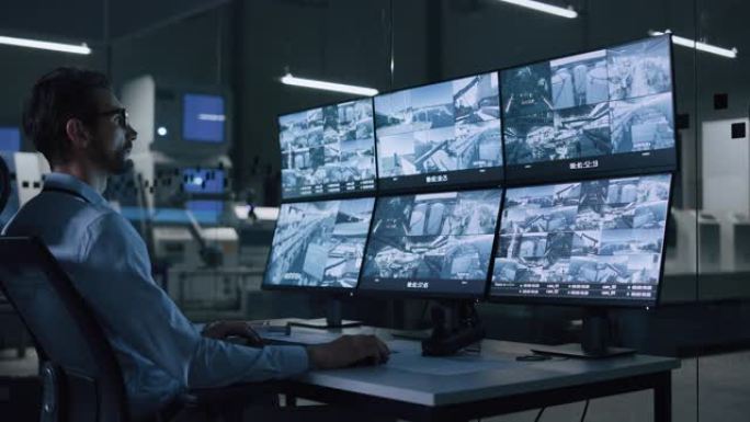 工业4.0现代工厂: 安全操作员控制车间生产线的正常运行，使用带有屏幕显示监控摄像机镜头的计算机。高