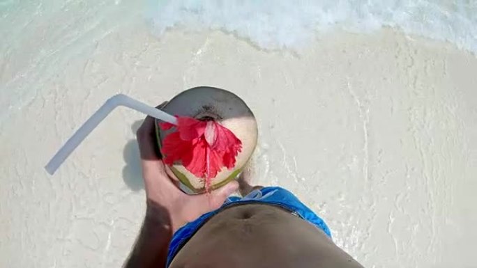 马尔代夫阳光明媚的热带海洋中，带着椰子饮料的女士个人观点男子涉水
