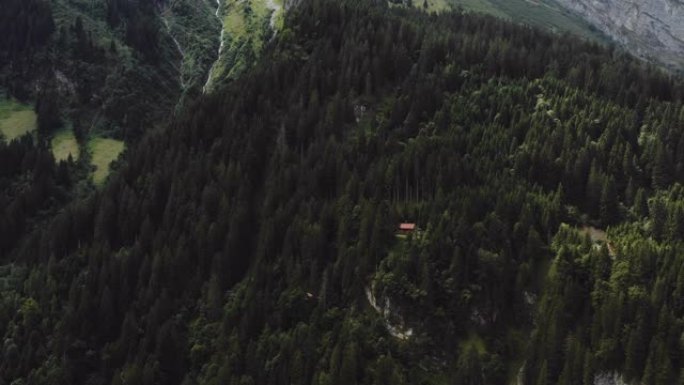 无人机放大了瑞士阿尔卑斯山树木间山林中隐藏的美丽小屋小屋。