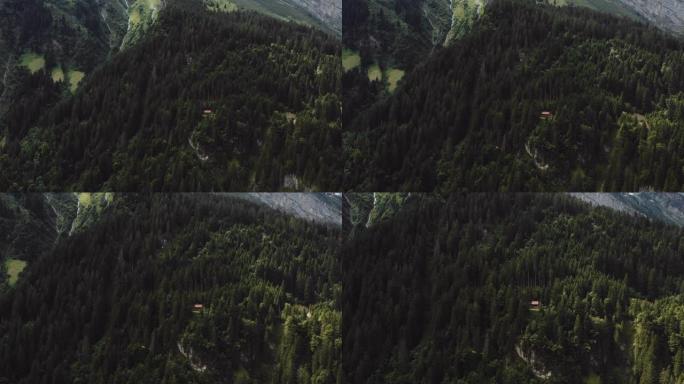 无人机放大了瑞士阿尔卑斯山树木间山林中隐藏的美丽小屋小屋。