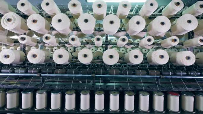 现代纺织厂的机器用白色纤维线轴工作。
