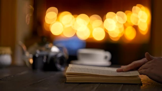 女人在舒适的咖啡馆翻着书看书。喝茶。晚上，圣诞装饰品。黄色圆形波克。4K