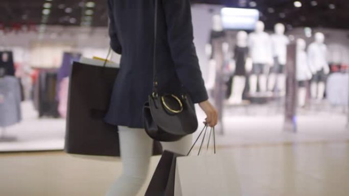 面目全非的女人带着购物袋穿过购物中心