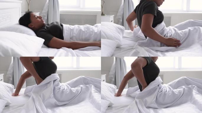 生病的非洲妇女在不舒服的床上醒来时感到背痛