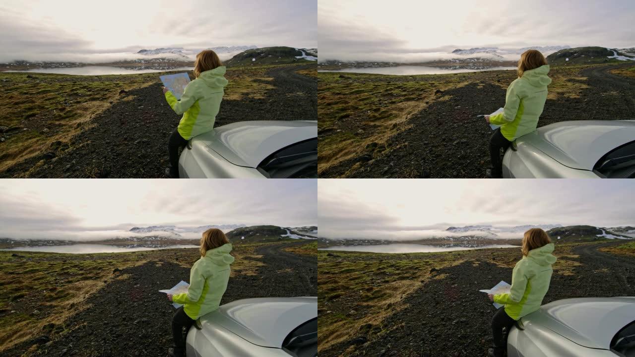 WS女人，地图站在汽车上，俯瞰着冰岛的偏远景观