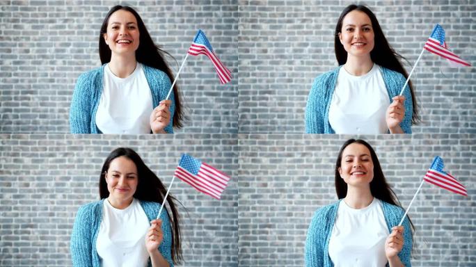 肖像可爱的女孩举着美国国旗和微笑的砖墙背景