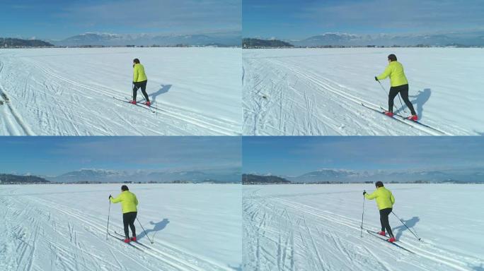 空中: 穿着五颜六色的夹克沿着女人在雪地里的小径滑雪。