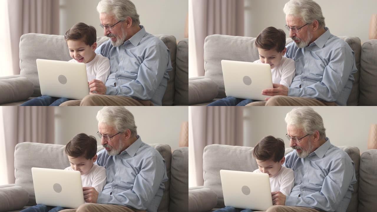 快乐的老爷爷和小孙子笑着看着笔记本电脑