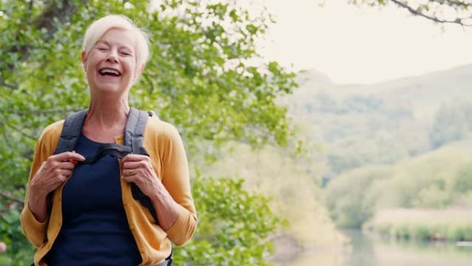 英国湖区沿河徒步旅行的笑女老人的慢动作肖像
