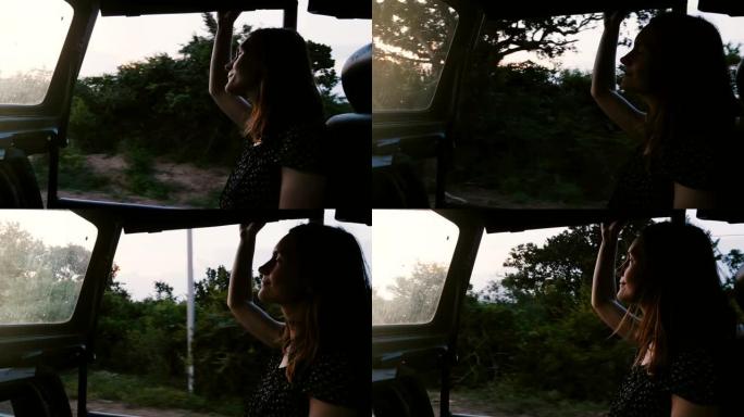 年轻快乐美丽的女游客微笑着，在日落森林的游览车里享受大气的野生动物园之旅。