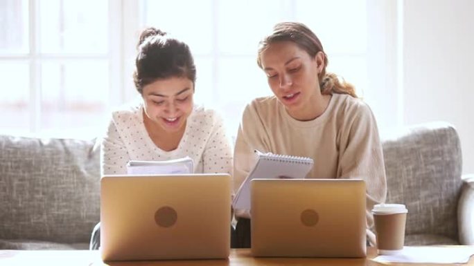 两个快乐多样的女生学生朋友一起在家学习