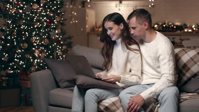 一对使用笔记本电脑的年轻夫妇在圣诞节通过视频通话与朋友交流。