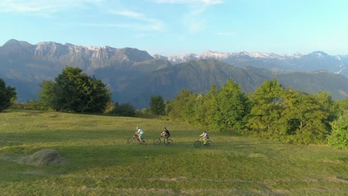 无人机: 沿着三个朋友骑着电动自行车在草地上飞翔。